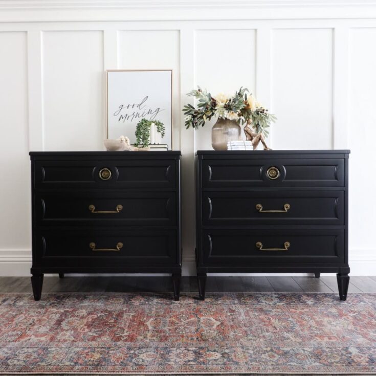 Two black dressers with brass handles, floral arrangement, décor, and a framed quote on top
