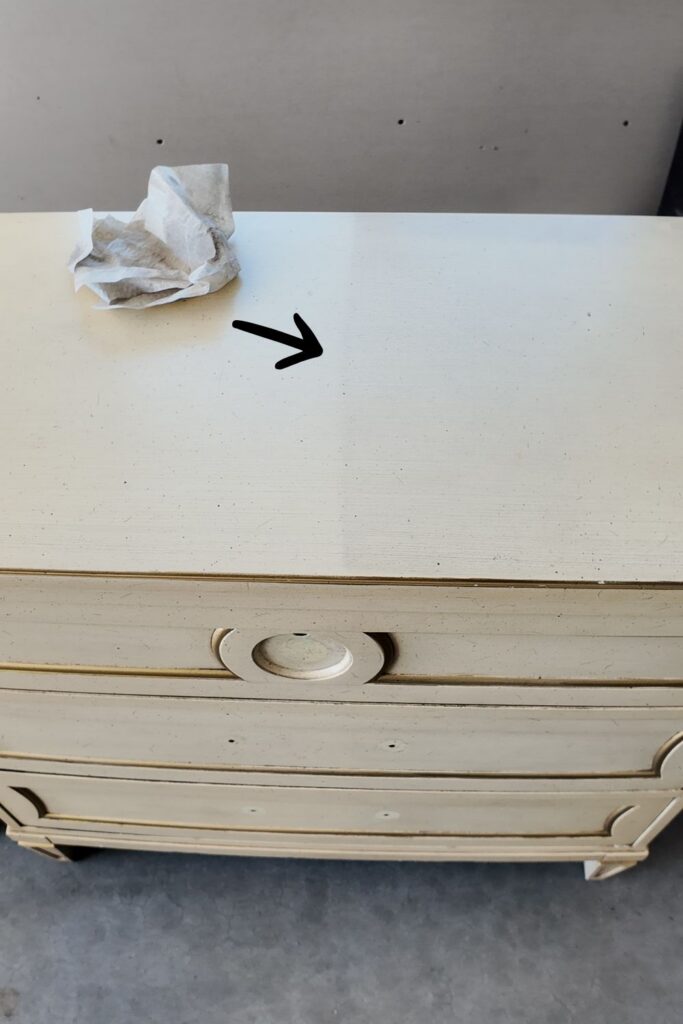 Arrow showing half of nightstand top cleaned by Surface Prep wipes