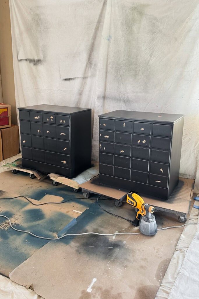 Two black nightstands with filler spots sit on dollies in a workshop