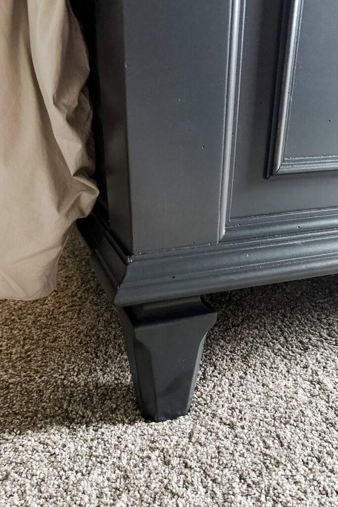 Close up view of a dark wood footboard on beige carpet.
