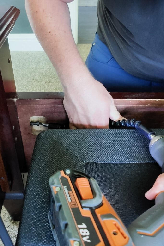 Person using a power drill with extender to unscrew bed frame