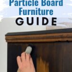 A hand painting a wooden cabinet with black paint; text reads Painting Particle Board Furniture Guide..