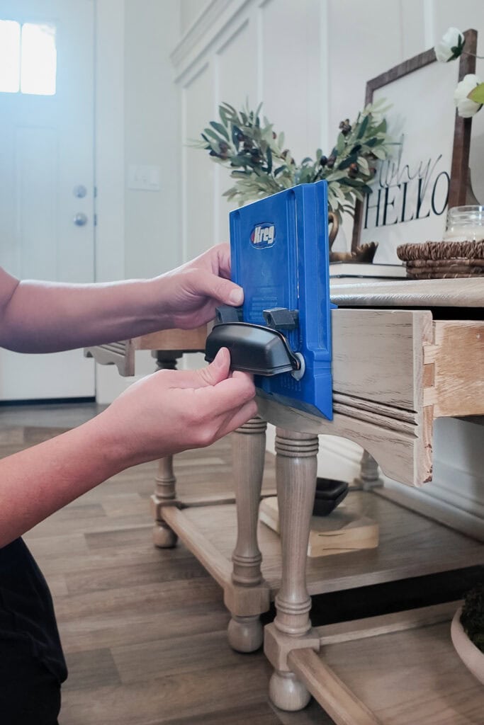 Person using a Kreg hardware jig to measure or mark for cup pull