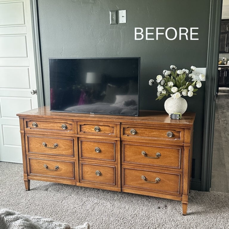 Orangey wooden dresser with TV and floral vase against a dark wall labeled BEFORE in white text.