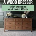 A wood dresser sits on a carpet in front of green paneled walls, decorated with flowers and candles.