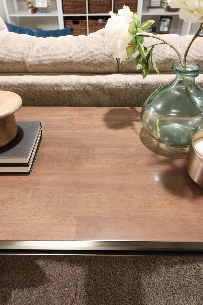 Wooden table with books, a wooden container, a green glass vase, and a candle.