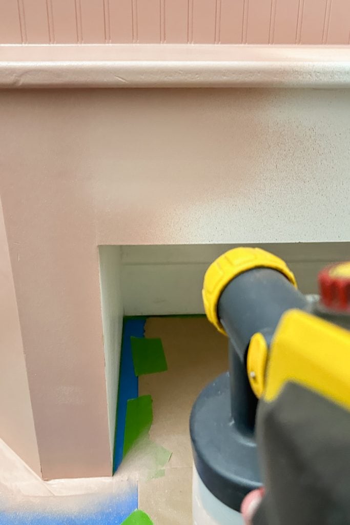 A paint sprayer is being used to apply paint on bench