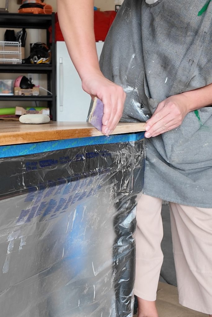 Person sanding the edge of a wooden top