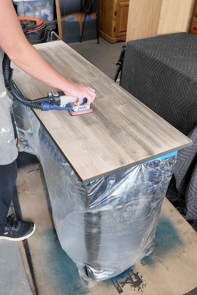 Person sanding a wooden tabletop with sander