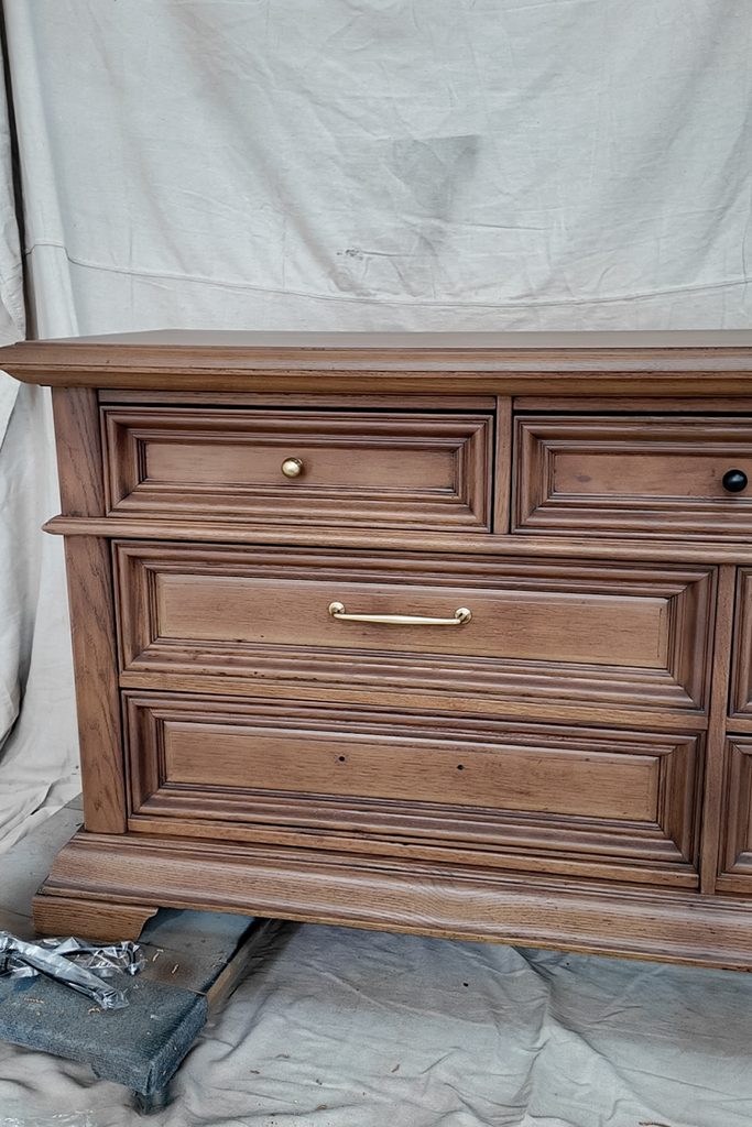 A wooden dresser with two small top drawers and two large bottom drawers featuring various metal hardware.